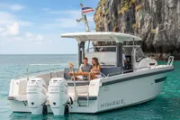 2022 Nimbus T11 boat cruising near rocky cliffs with people enjoying a meal on deck.