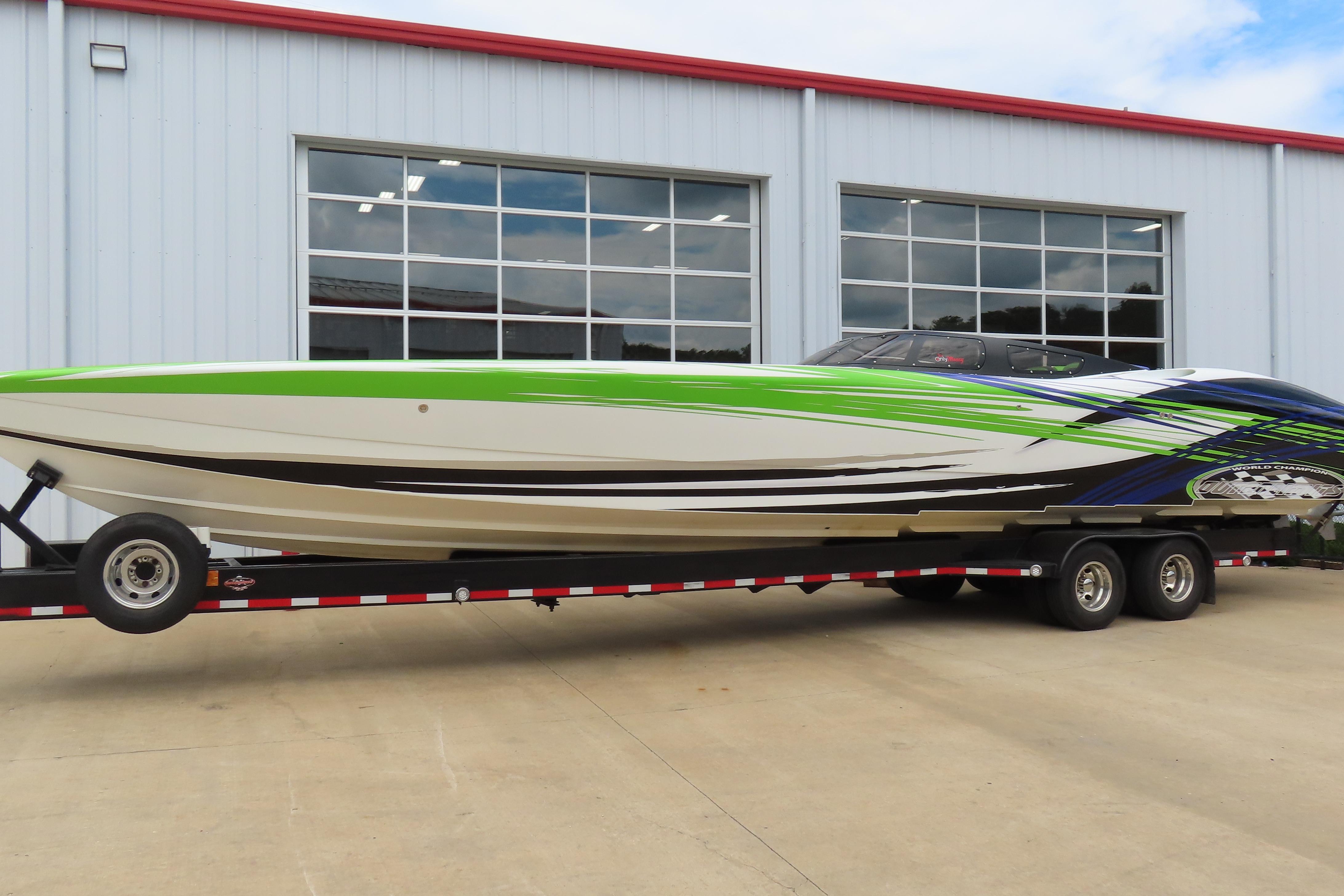 2007 Outerlimits 44 GTX powerboat on trailer, featuring vibrant green and blue graphics.