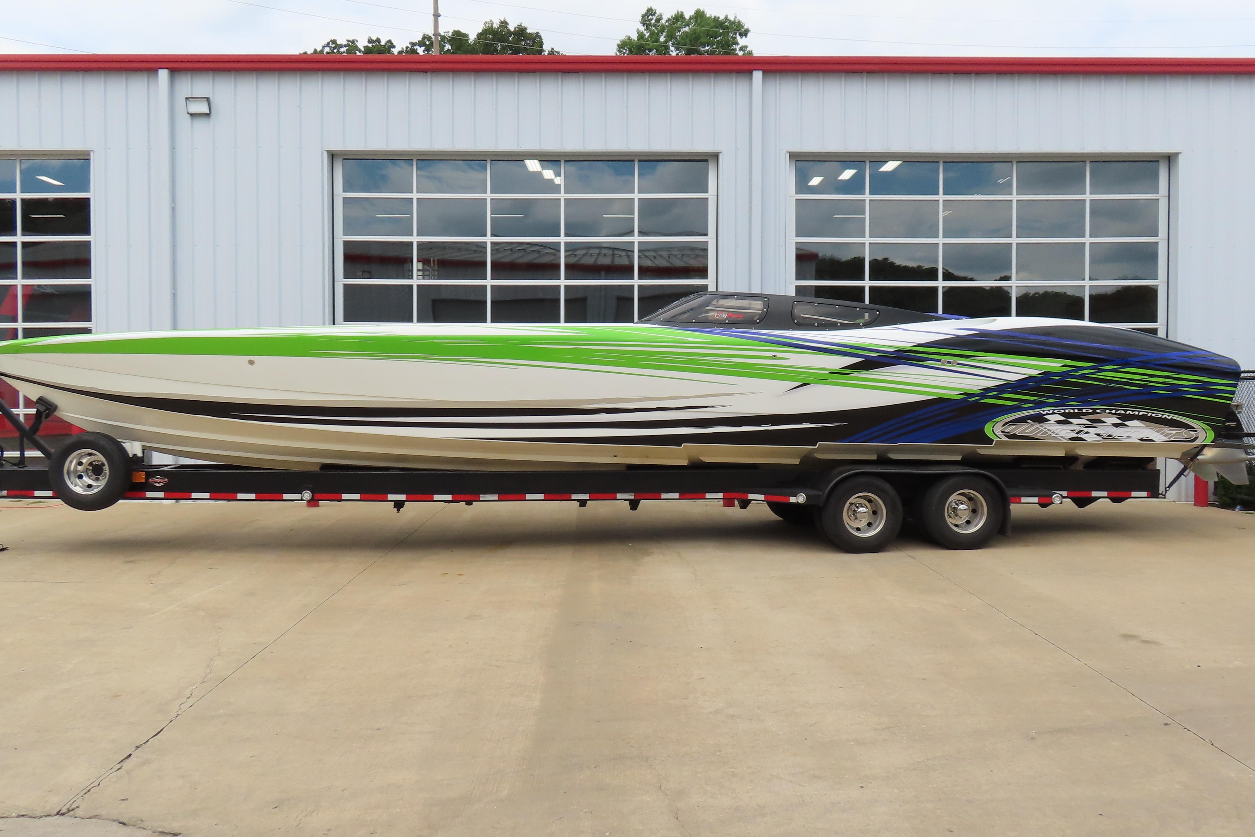 2007 Outerlimits 44 GTX speedboat with vibrant green and blue design on trailer.
