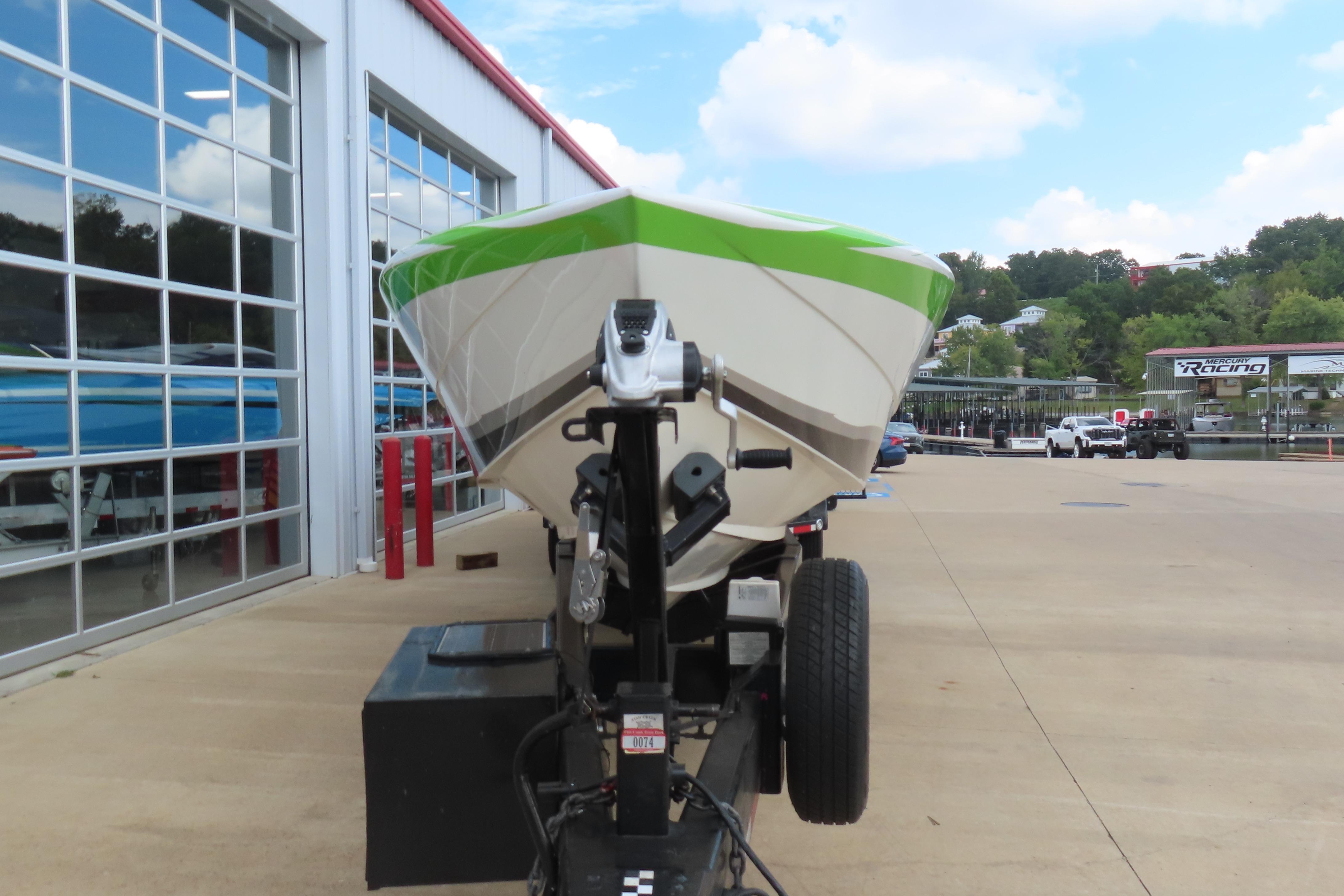 2007 Outerlimits 44 GTX boat on trailer outside a garage, featuring a green and white hull.