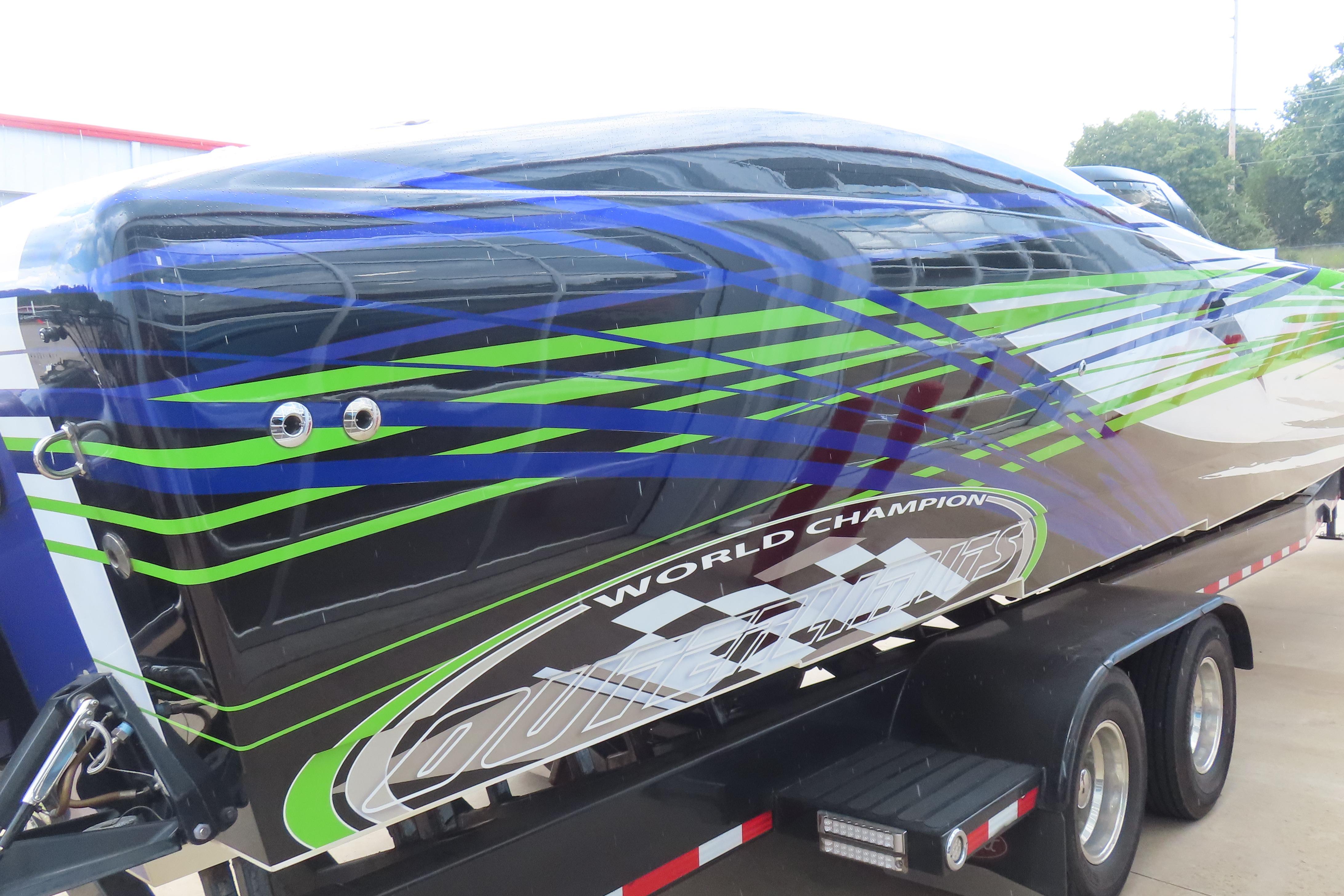 2007 Outerlimits 44 GTX powerboat with vibrant blue and green graphics on a trailer.