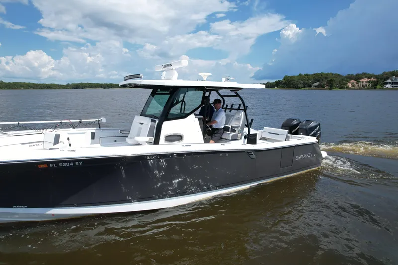  Yacht Photos Pics 2021 Blackfin 332 CC boat cruising on a lake under a partly cloudy sky.