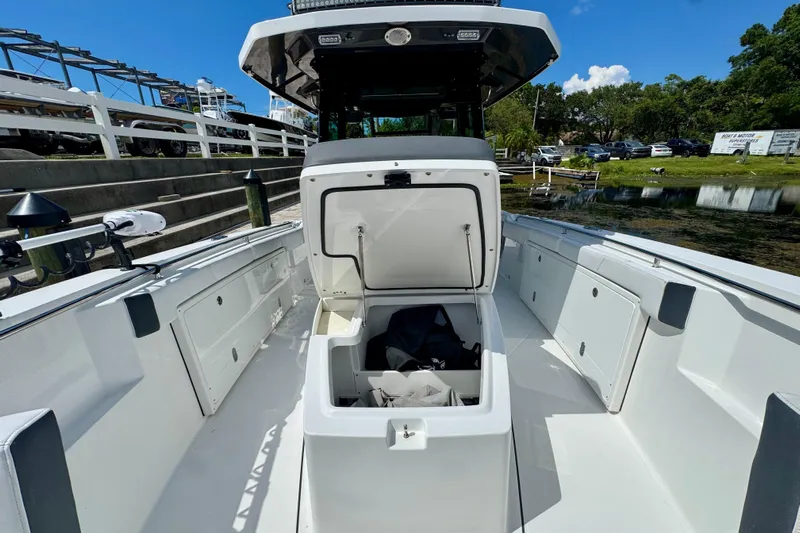  Yacht Photos Pics 2021 Blackfin 332 CC boat with open storage compartment, docked near a serene waterfront.