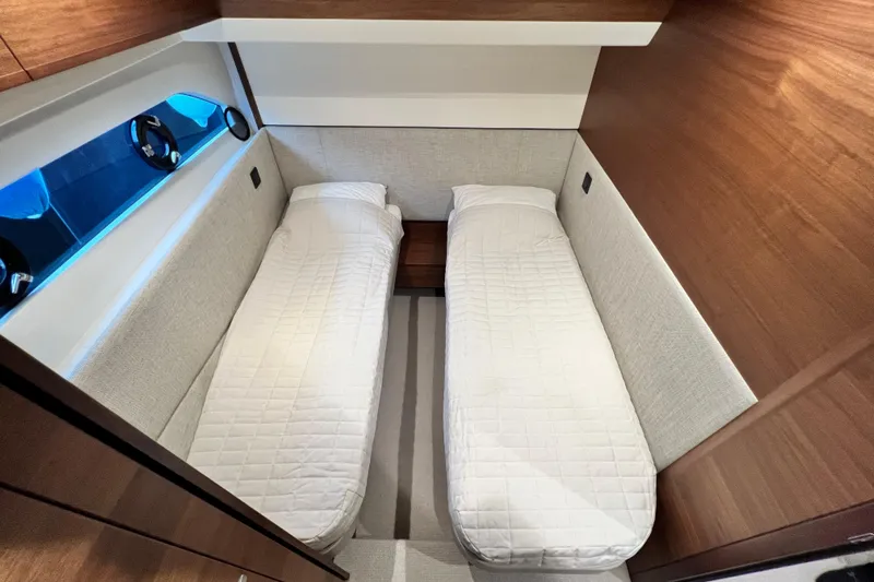  Yacht Photos Pics 2021 Princess F55 yacht cabin with twin beds, modern wood finish, and porthole window.
