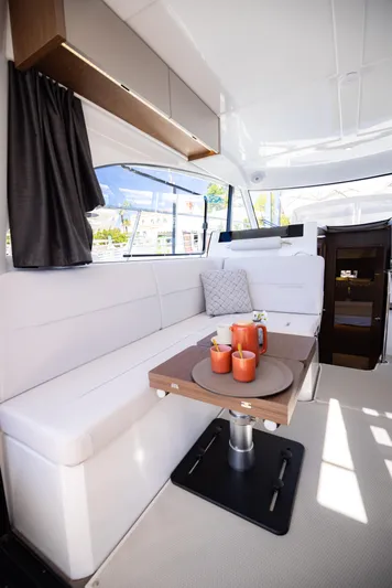  Yacht Photos Pics 2026 Beneteau Antares 11 interior with white seating and wooden table.