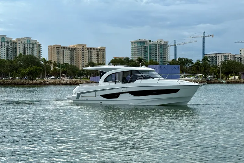  Yacht Photos Pics 2026 Beneteau Antares 11 yacht cruising near urban waterfront with buildings and cranes.