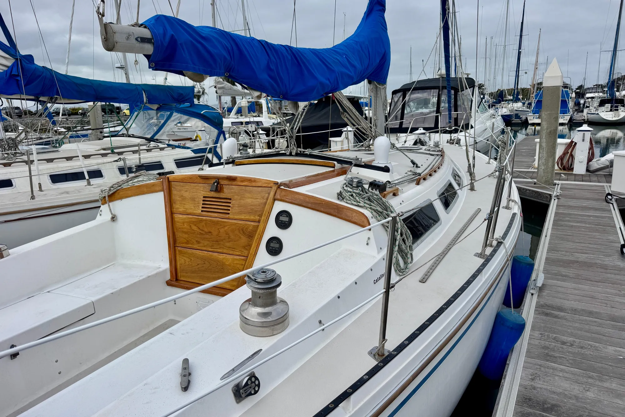 1986 Catalina 36 sailboat docked in marina, featuring blue sail cover and wooden hatch.