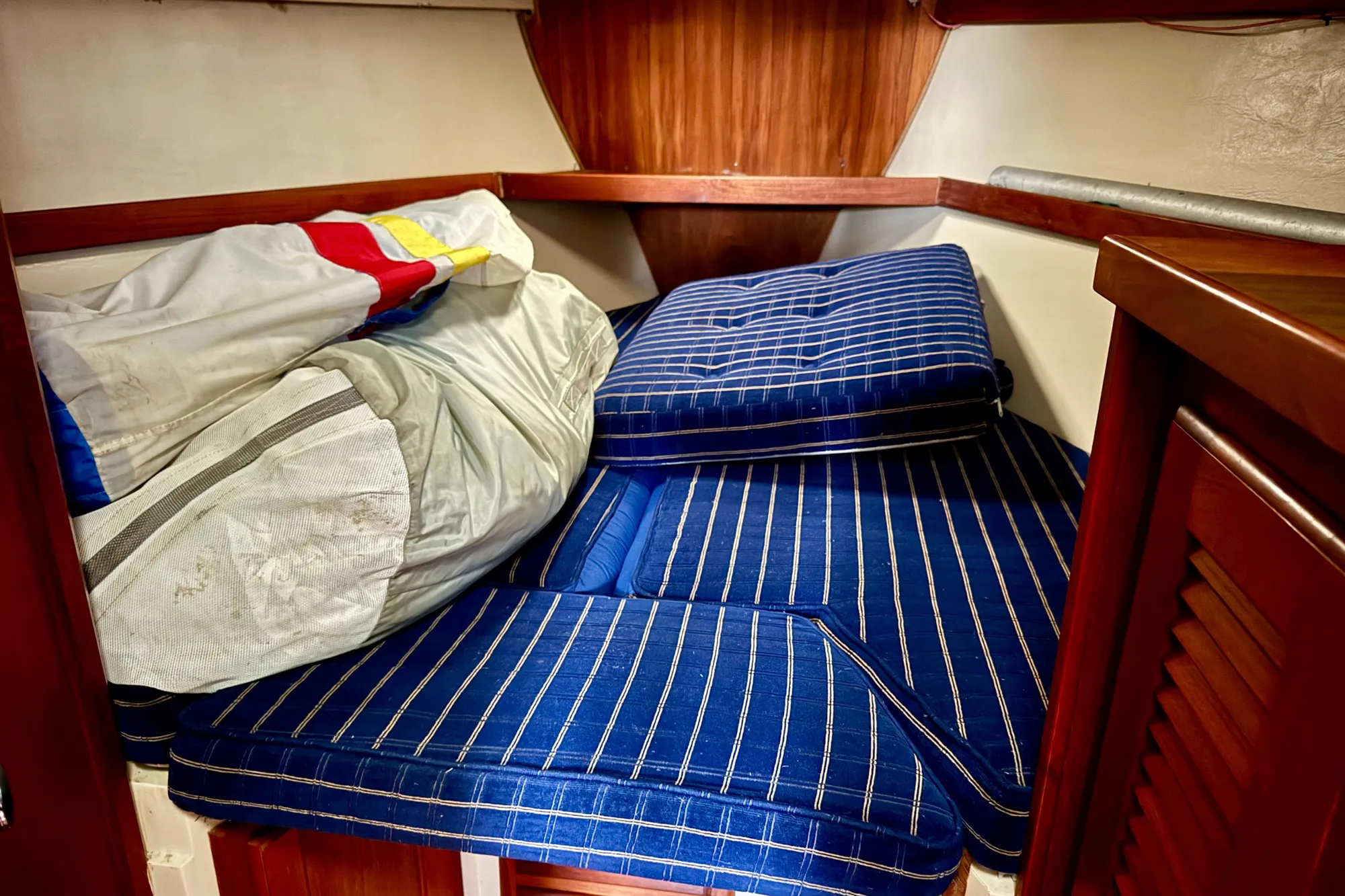 Cozy cabin interior of 1986 Catalina 36 sailboat with striped cushions and stored sail.