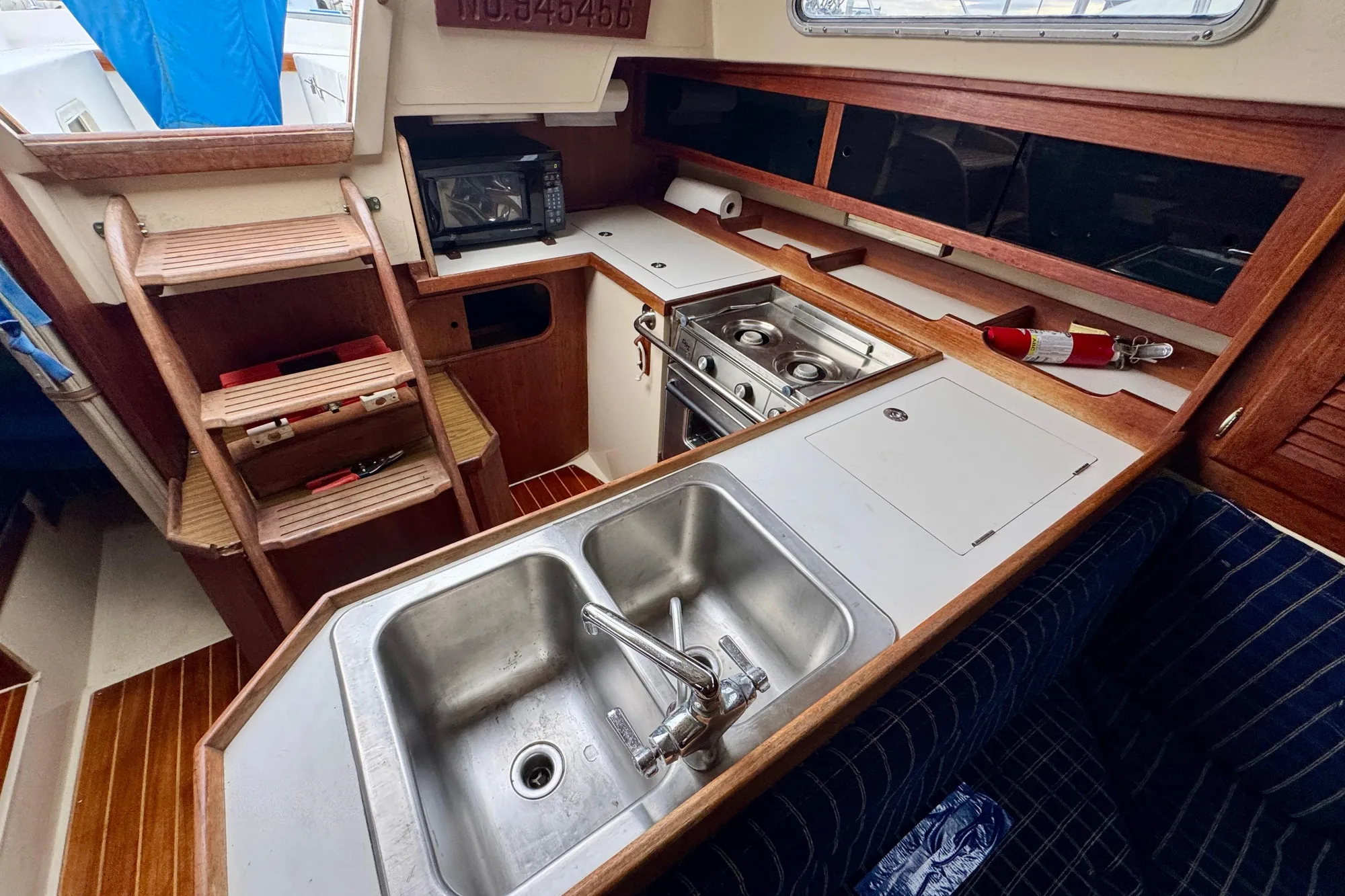 Interior of 1986 Catalina 36 sailboat kitchen with sink, stove, and wooden cabinetry.