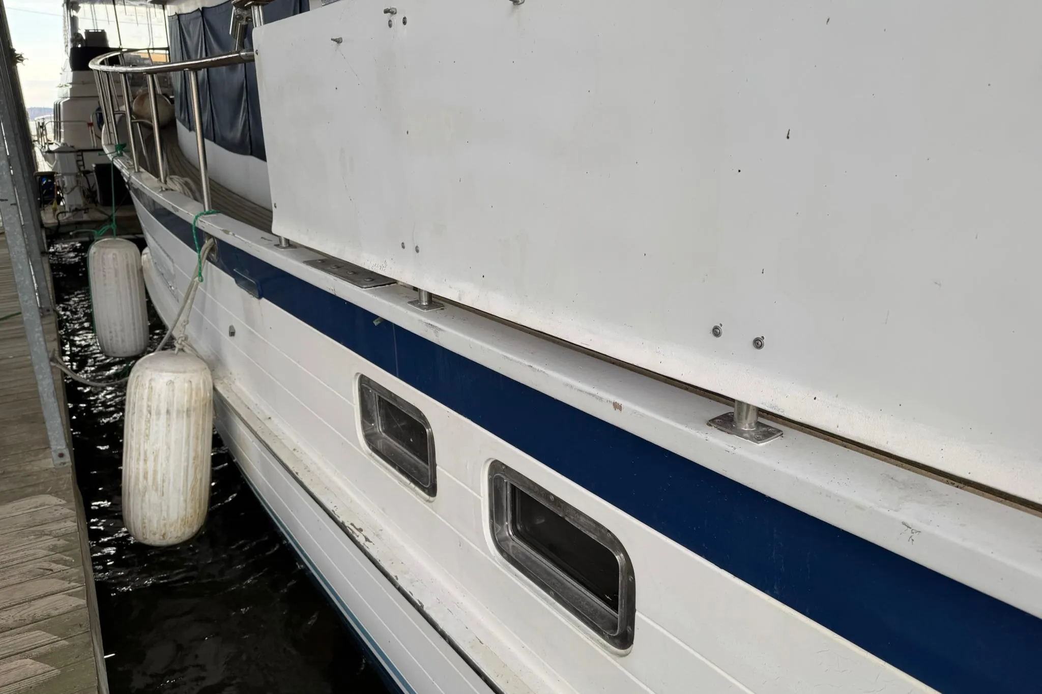 1991 DeFever 44 yacht docked with fenders, showcasing side view and windows.