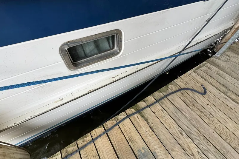 Sandial Yacht Photos Pics Side view of a 1991 DeFever 44 boat docked, showing a window and blue rope.