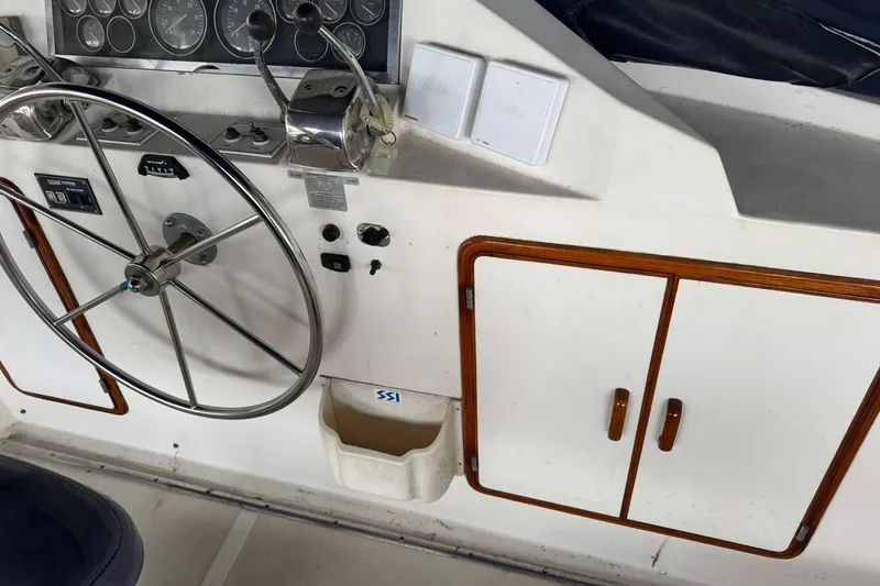 Sandial Yacht Photos Pics 1991 DeFever 44 yacht helm with steering wheel, gauges, and wooden cabinet.