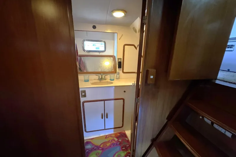 Sandial Yacht Photos Pics Bathroom interior of 1991 DeFever 44 yacht with wooden cabinetry and colorful rug.