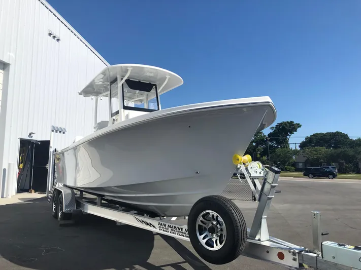  Yacht Photos Pics 2026 Pair Customs 24 Center Console DV boat on trailer, parked outside a building.