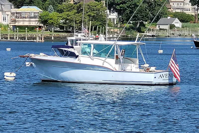  Yacht Photos Pics 1984 Sunny Briggs 37 Express boat on water, American flag, scenic background.