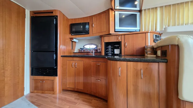  Yacht Photos Pics 2005 Carver 36 Mariner yacht interior with wood cabinetry, appliances, and cozy seating.