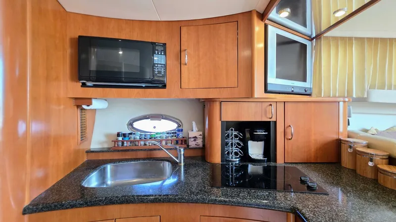 Yacht Photos Pics 2005 Carver 36 Mariner kitchen with microwave, sink, stove, and TV in wooden cabinetry.