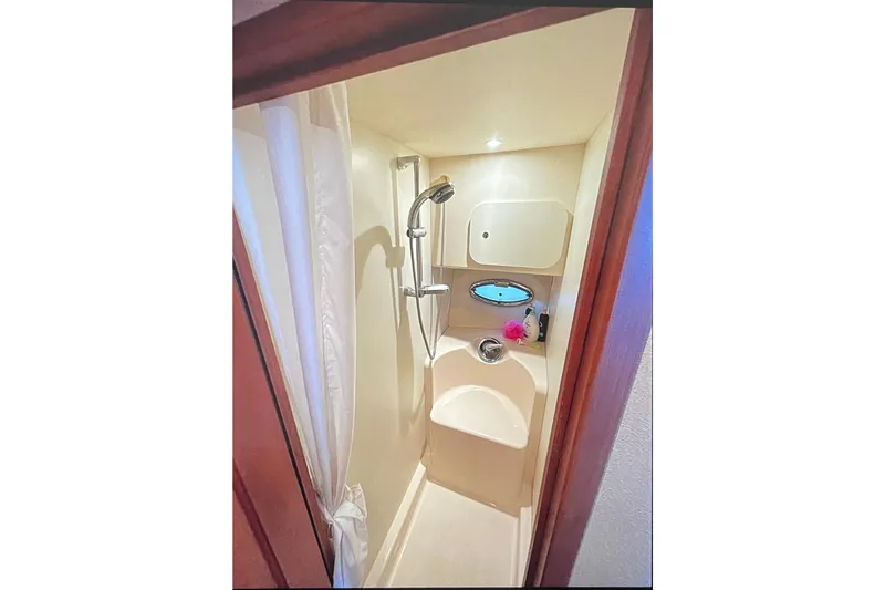 Northern Comfort Yacht Photos Pics Compact shower area in 2005 Silverton 34 Convertible boat, featuring modern fixtures and porthole.