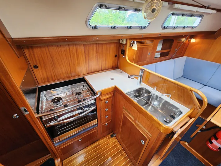 Ceres Yacht Photos Pics 2016 Hallberg-Rassy 342 yacht interior with wooden cabinetry, stove, sink, and seating area.