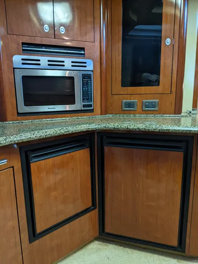 Yacht Photos Pics 2006 Sea Ray 44 Sundancer galley with microwave, granite countertop, and wooden cabinetry.