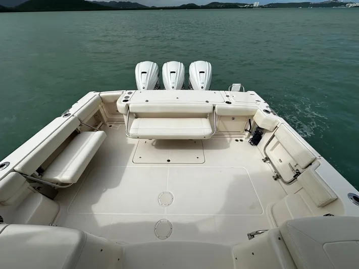  Yacht Photos Pics 2021 Grady-White Express 370 boat deck with triple outboard engines on calm water.