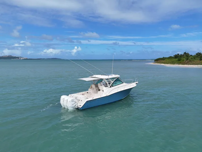  Yacht Photos Pics 2021 Grady-White Express 370 boat cruising in clear blue waters near a tropical shoreline.