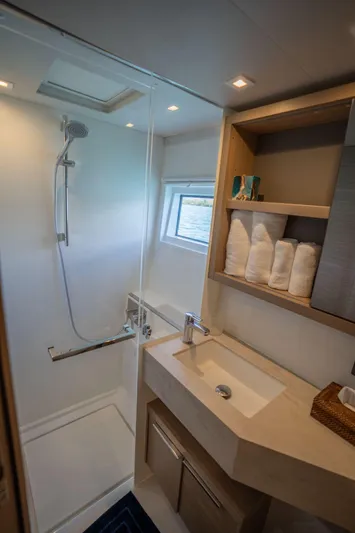 Blossom Yacht Photos Pics Modern bathroom in 2024 Lagoon 46 yacht with shower, sink, and storage shelves.