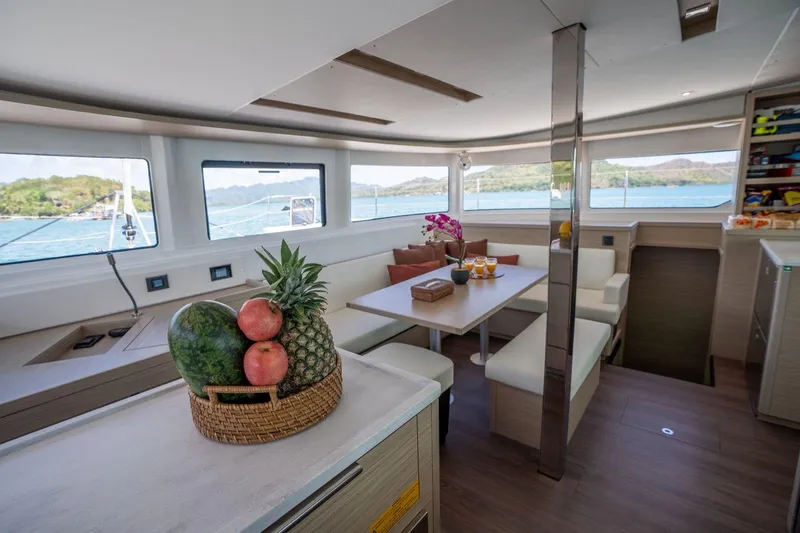 Blossom Yacht Photos Pics Luxurious interior of 2024 Lagoon 46 catamaran with fruit basket and scenic ocean view.