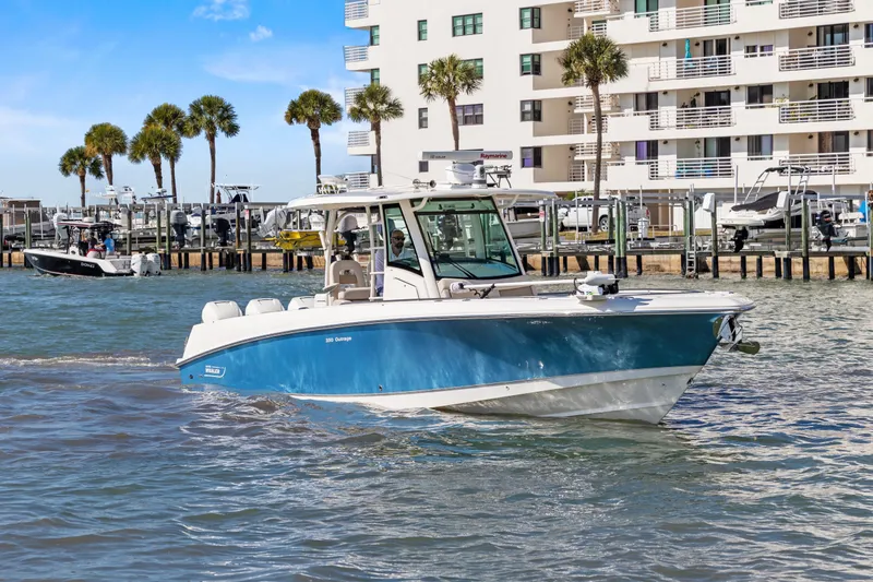  Yacht Photos Pics 2017 Boston Whaler 350 Outrage boat cruising near waterfront buildings and palm trees.