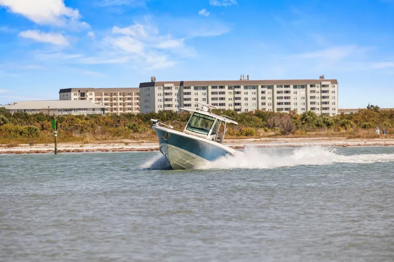  Yacht Photos Pics 2017 Boston Whaler 350 Outrage cruising near coastal buildings under blue sky.