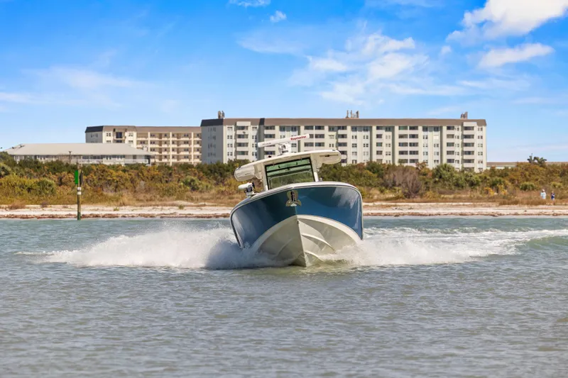 Yacht Photos Pics 2017 Boston Whaler 350 Outrage cruising in coastal waters with buildings in the background.