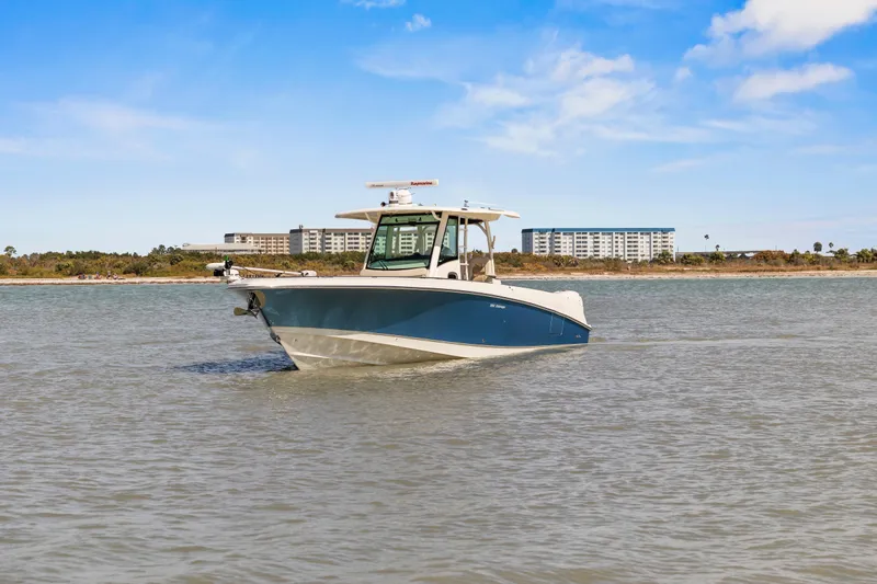  Yacht Photos Pics 2017 Boston Whaler 350 Outrage boat on calm water with buildings in the background.