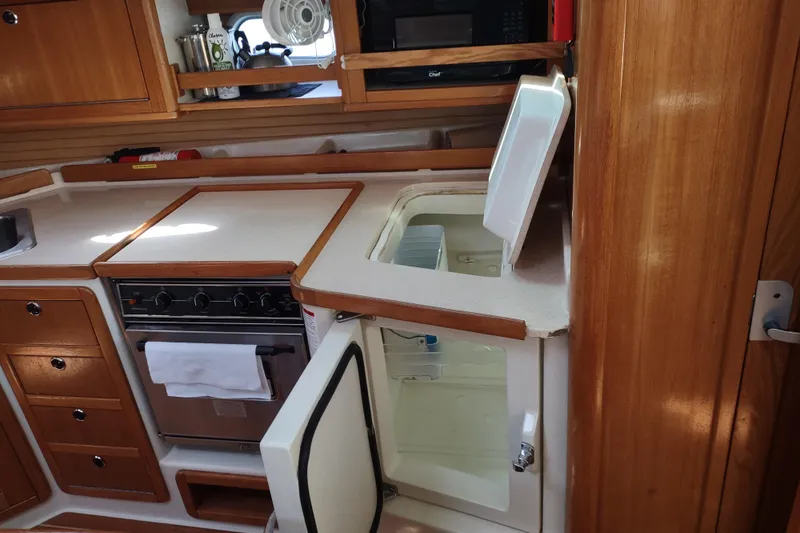 Spotted Drum II Yacht Photos Pics 2004 Catalina 42 Mk II yacht kitchen with stove, fridge, and wooden cabinetry.