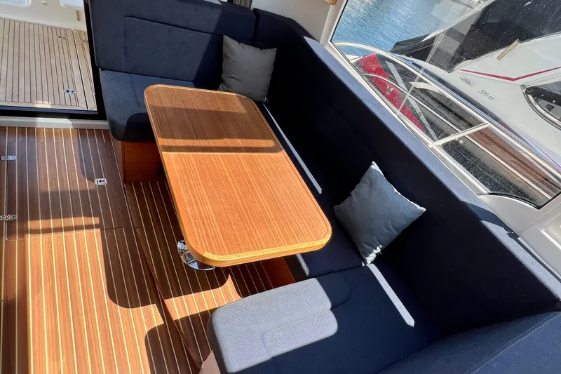 Kala Yacht Photos Pics Interior of 2018 Nimbus 365 Coupe with wooden table and blue seating.
