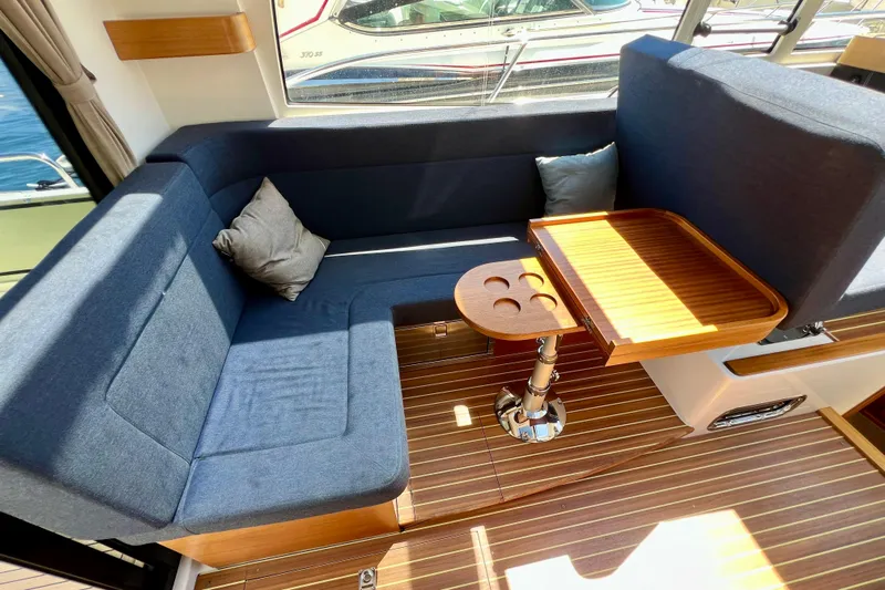 Kala Yacht Photos Pics Interior of 2018 Nimbus 365 Coupe with blue seating and wooden table.
