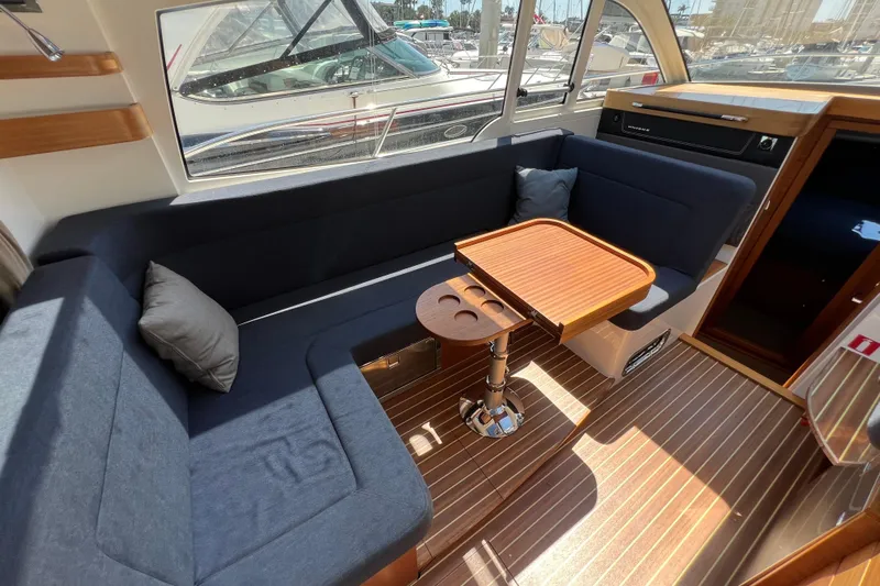 Kala Yacht Photos Pics Interior of 2018 Nimbus 365 Coupe with cozy seating and wooden table.