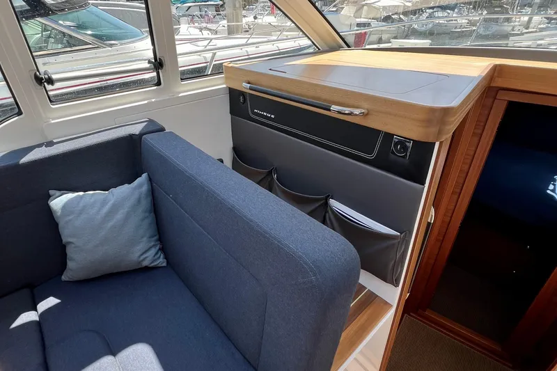 Kala Yacht Photos Pics Interior of 2018 Nimbus 365 Coupe with blue sofa and wooden cabinetry.