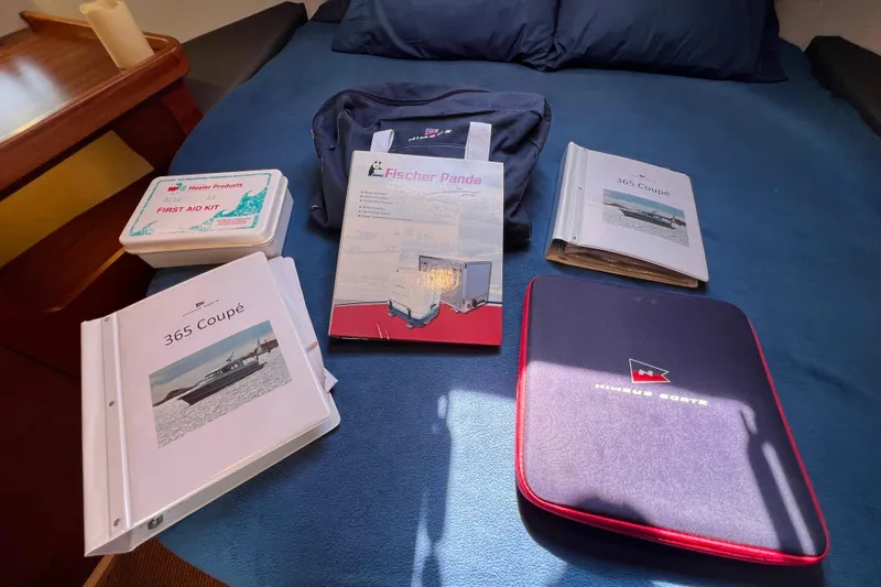 Kala Yacht Photos Pics Nimbus 365 Coupe 2018 manuals and first aid kit on a blue bedspread.