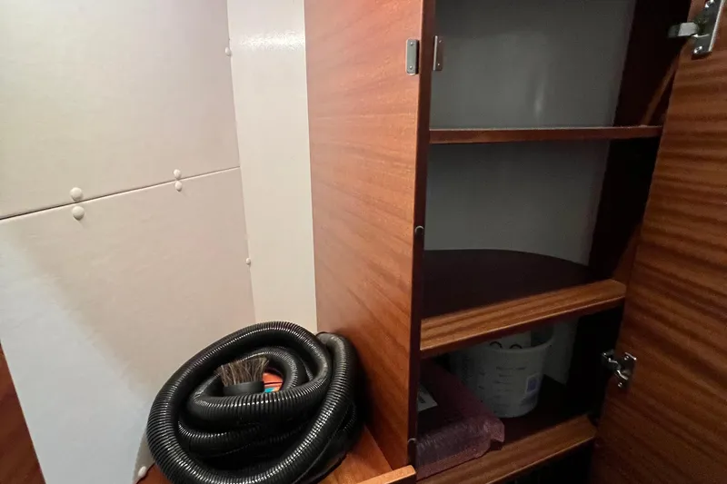 Kala Yacht Photos Pics Interior storage space of 2018 Nimbus 365 Coupe with wooden shelves and coiled hose.