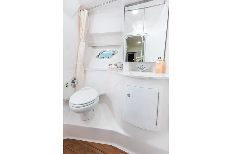 Popsicle Yacht Photos Pics 2019 Regal 35 Sport Coupe bathroom with toilet, sink, mirror, and porthole window.