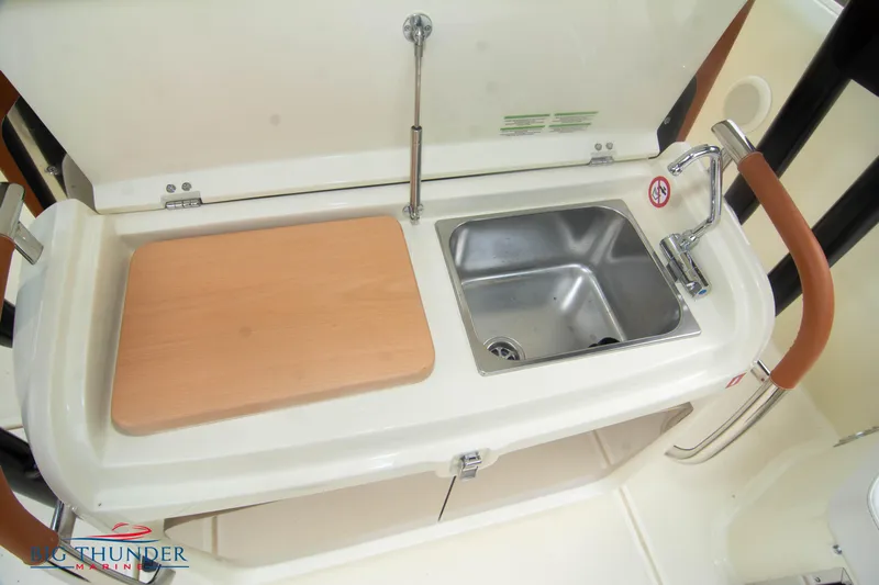  Yacht Photos Pics 2024 Invictus TT280S boat sink and cutting board in compact kitchen area.