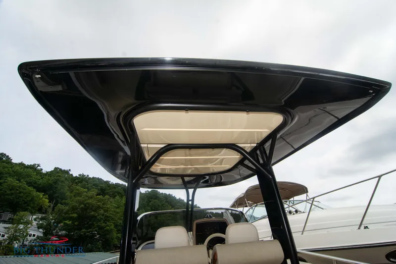  Yacht Photos Pics 2024 Invictus TT280S boat with sleek black canopy, docked near lush greenery.