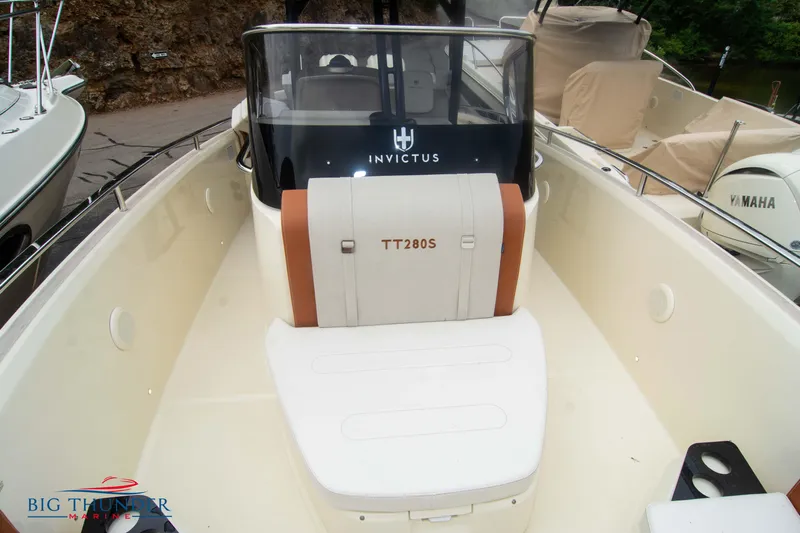  Yacht Photos Pics 2024 Invictus TT280S boat interior with seating and console, docked near other boats.