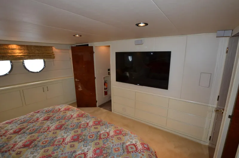 Reel Life Yacht Photos Pics Luxurious bedroom interior of 1996 Hatteras 82 Convertible yacht with TV and portholes.