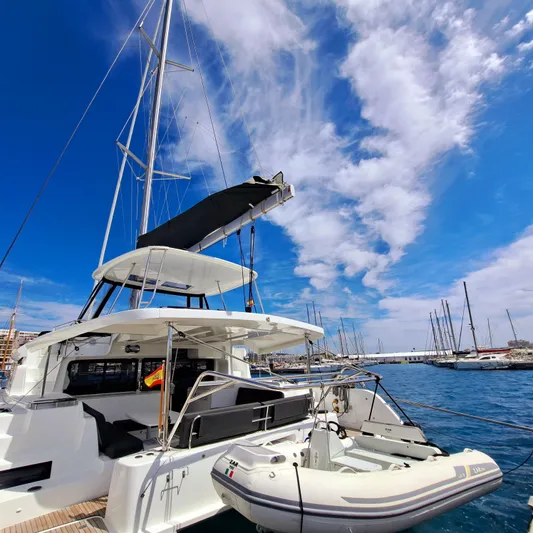  Yacht Photos Pics 2023 Lagoon 46 catamaran docked at marina under clear blue sky.