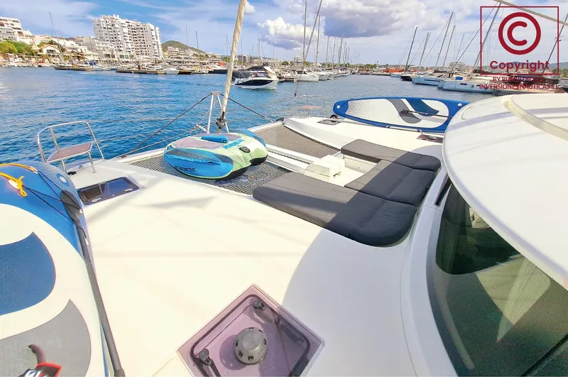  Yacht Photos Pics 2023 Lagoon 46 catamaran docked in a marina, featuring spacious deck and seating area.