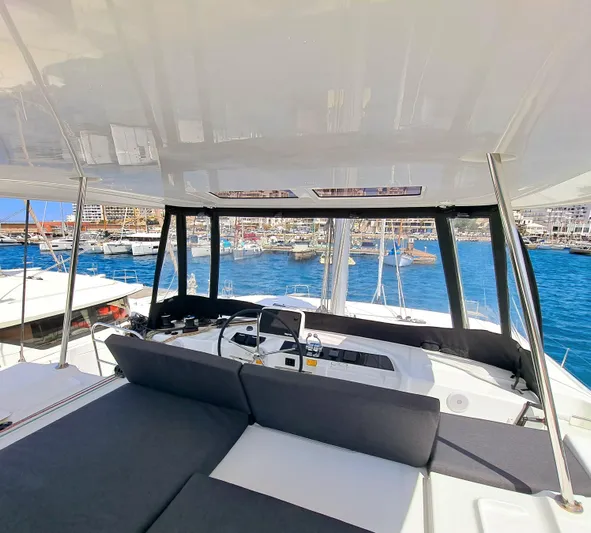  Yacht Photos Pics 2023 Lagoon 46 yacht interior with marina view, featuring modern seating and navigation equipment.