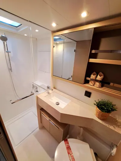  Yacht Photos Pics Modern bathroom in 2023 Lagoon 46 yacht with shower, sink, and storage shelves.