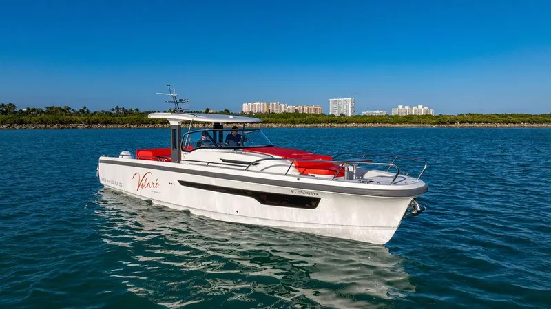 Volare Yacht Photos Pics 2023 Nimbus T11 boat cruising on clear blue water with cityscape in the background.