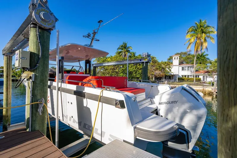 Volare Yacht Photos Pics 2023 Nimbus T11 boat docked, featuring red seating and Mercury engine, with tropical backdrop.